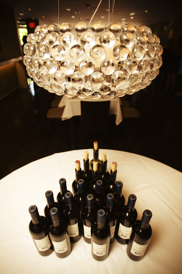 wine bottles arranged in pyramid formation underneath chandelier - wedding photo by top Denver based wedding photographer Hardy Klahold